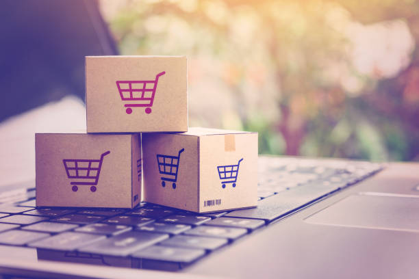 Online shopping / ecommerce and delivery service concept : Paper cartons with a shopping cart or trolley logo on a laptop keyboard, depicts customers order things from retailer sites via the internet.